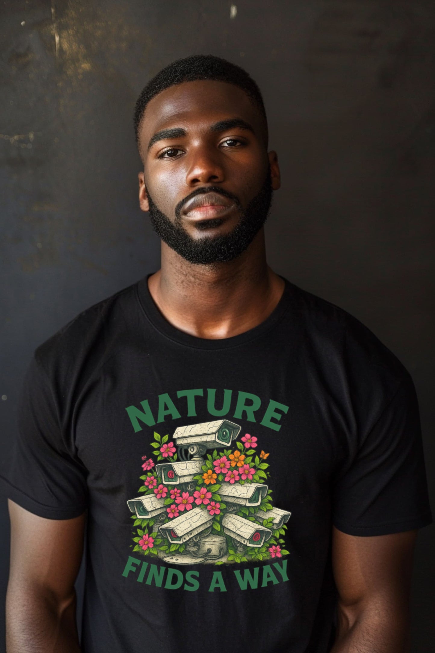 Man wearing Nature Finds a Way t-shirt in black with flowers growing over surveillance camera design