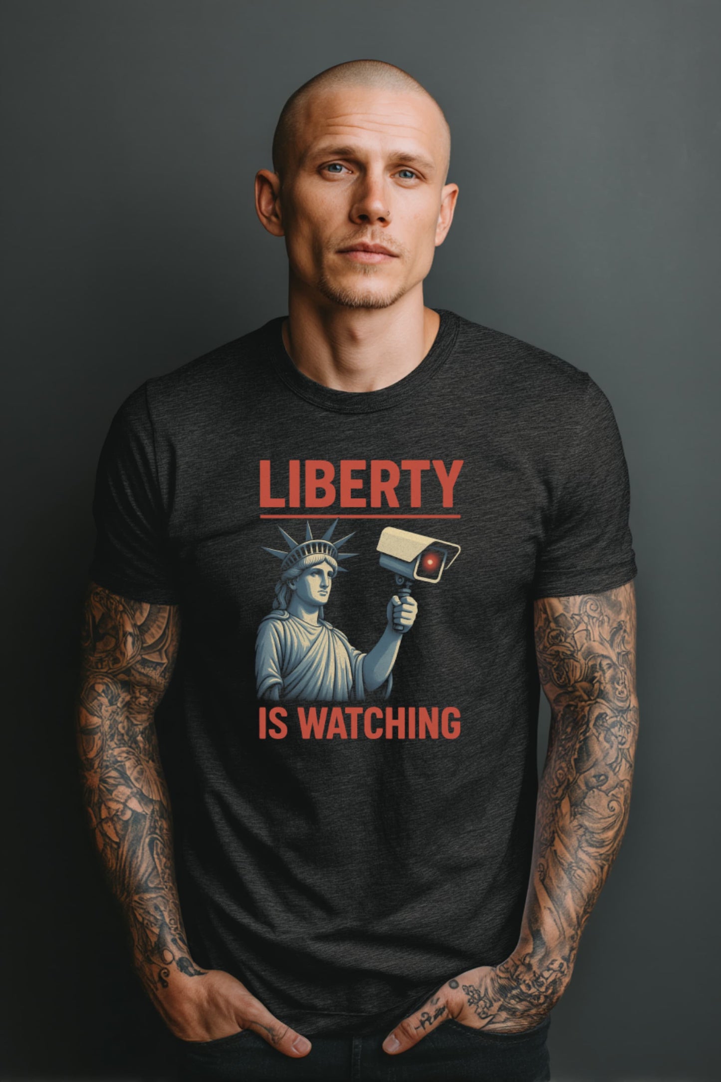 Man wearing Liberty Is Watching t-shirt in dark grey with bold surveillance protest graphic